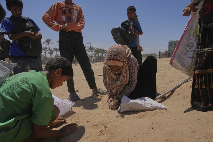 فلسطينيون يجمعون العدس عن الأرض بعد إنزال مساعدات جوًا بالمظلات وسط قطاع غزة، الإثنين 4 أغسطس 2025. 
