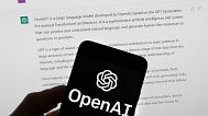 The OpenAI logo is seen on a mobile phone in front of a computer screen which displays output from ChatGPT, March 21, 2023, in Boston