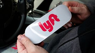 In this Jan. 31, 2018, photo, a Lyft driver holds a Lyft logo before installing it on his car in Pittsburgh
