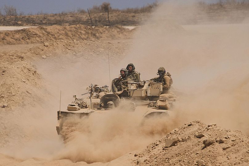 Israeli soldiers drive on their armoured personnel carrier back from inside the northern Gaza Strip into southern Israel, 29 July, 2025