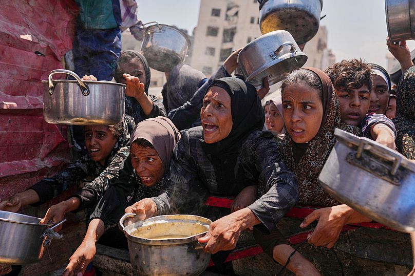 Palestinians struggle to get donated food at a community kitchen in Gaza City, 4 August, 2025