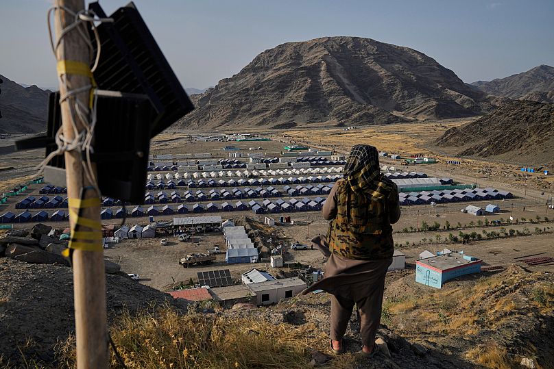 A Taliban fighter stands on a hill overlooking a camp housing Afghan refugees who have been repatriated from Pakistan in Torkham, 31 May, 2025