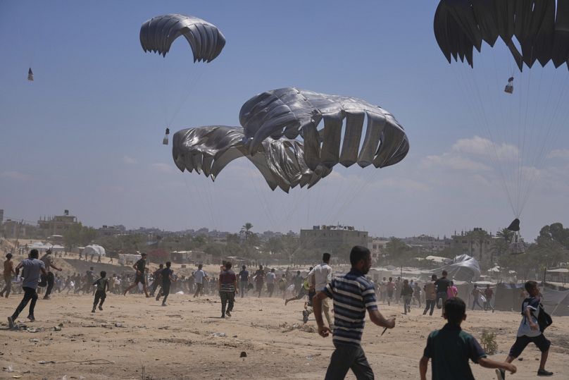 Palestinians rush to collect humanitarian aid airdropped by parachutes into Zawaida in the central Gaza Strip, Monday, Aug. 4, 2025. 