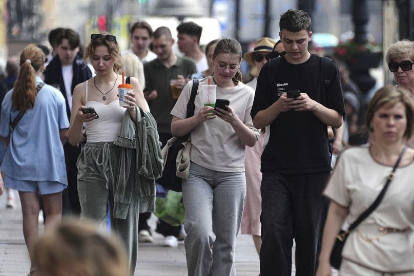 Rusya'nın St. Petersburg kentinde telefonuna bakarak yürüyen insanlar, 14 Temmuz 2025