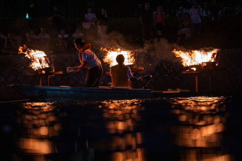 Bonfires are lit along the Motoyasu River in front of the Atomic Bomb Dome during a remembrance ceremony in Hiroshima on the eve of the 80th anniversary of the atomic bombing.