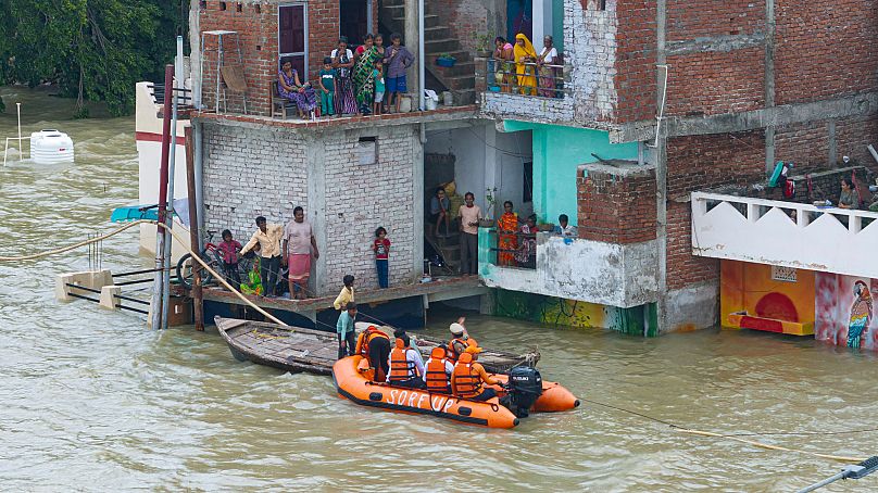 Membros da Força Estadual de Resposta a Desastres resgatam residentes presos numa área submersa de Prayagraj, 5 de agosto de 2025.
