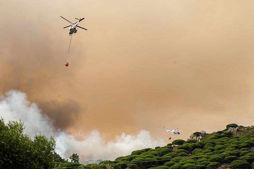 Firefighting helicopters drop water to extinguish a blaze in Torre de la Peña, southern Spain, Tuesday, Aug. 5, 2025.