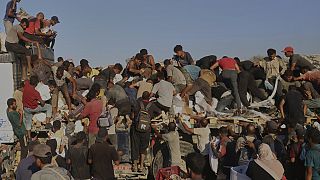 يكافح الفلسطينيون للحصول على الغذاء والمساعدات الإنسانية من خلف شاحنة أثناء في جنوب قطاع غزة، يوم الاثنين 4 أغسطس/آب 2025.