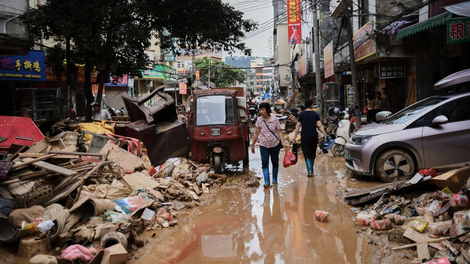 Residenti guadano i detriti lungo una strada colpita dall'alluvione nella contea di Huaiji, nella provincia meridionale cinese di Guangdong, 19 giugno 2025