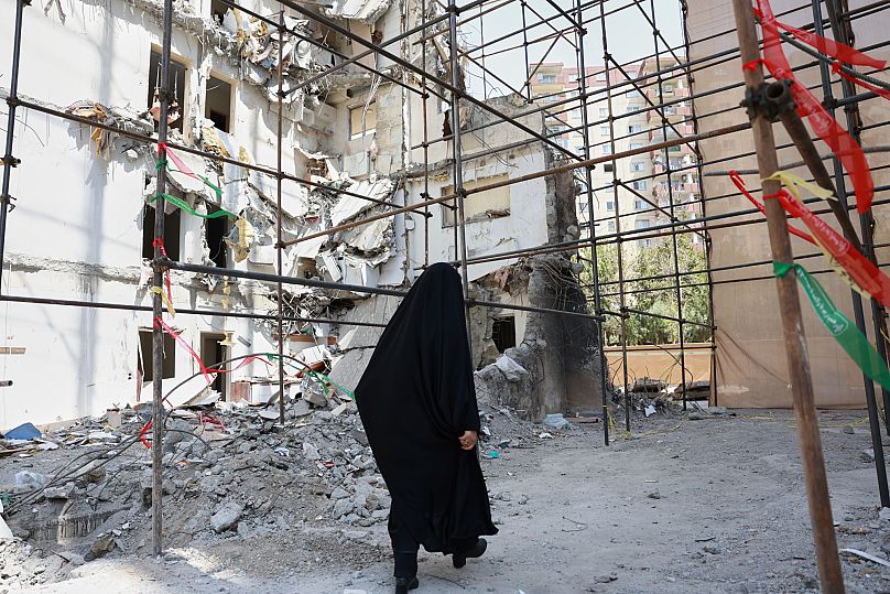 A woman walks past a building damaged in a deadly Israeli air strike at a residential compound in Tehran, 19 July, 2025