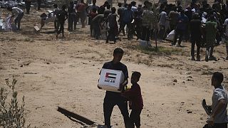 Palestinians collect humanitarian aid packages from the United Arab Emirates after they were airdropped into Deir Al-Balah, in the central Gaza Strip.