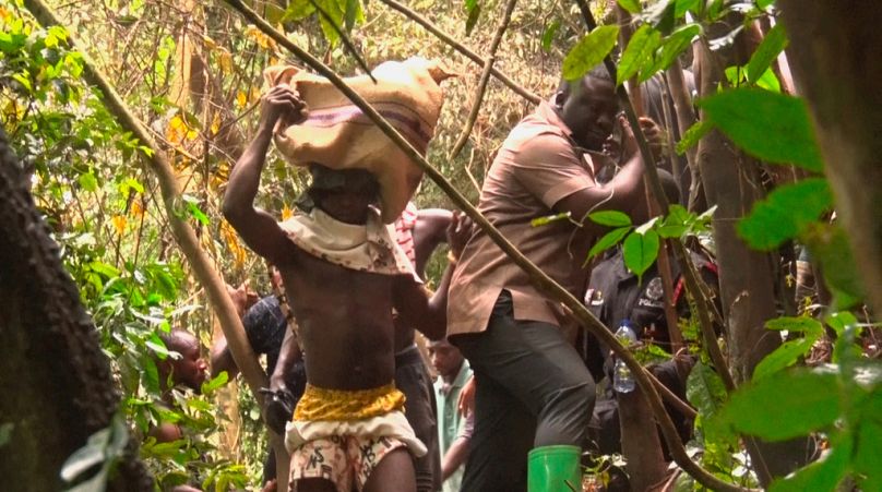 En esta imagen tomada de un video, un hombre lleva cuerpos recuperados del accidente de helicóptero militar en Sikaman, cerca de Adansi, región de Ashanti, Ghana.