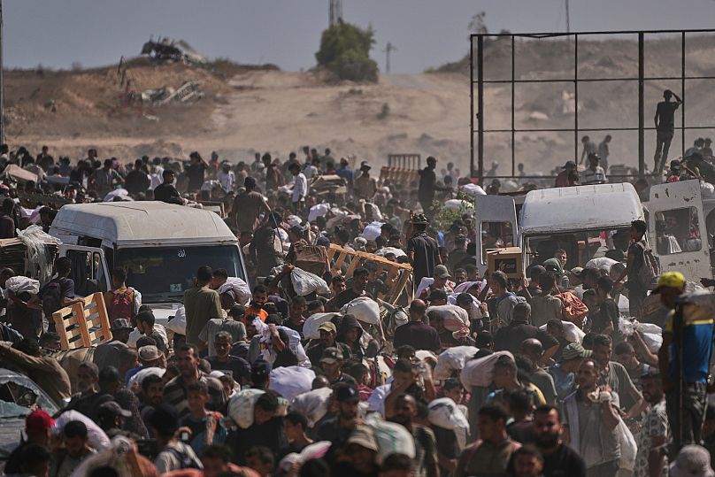 Palestinesi trasportano pacchi di aiuti umanitari vicino a un centro di distribuzione della Gaza Humanitarian Foundation a Netzarim, 4 agosto 2025