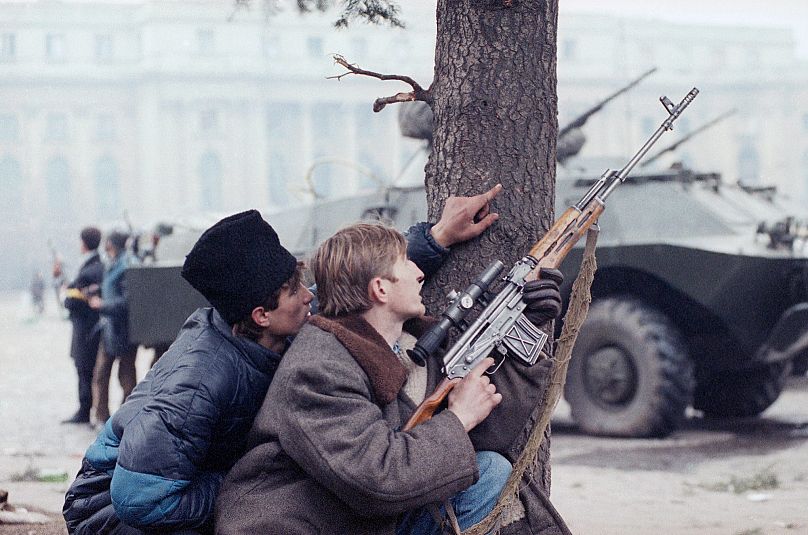 FILE:A member of the Romanian Civil Defence force in Bucharest readies his rifle trying to locate pro-Ceausescu forces who have continued to fire on citizens, 24 December 1989