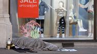 A homeless person sleeps in front of a closed clothing shop in London, 14 May, 2020 