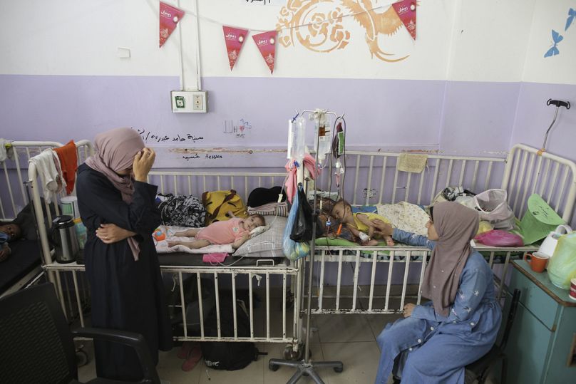  أميرة الجوجو، إلى اليسار، تقف بجانب ابنها يوسف الجوجو البالغ من العمر 10 أشهر، والذي يعاني من سوء التغذية في مستشفى شهداء الأقصى، وسط قطاع غزة في 1 يونيو 2024