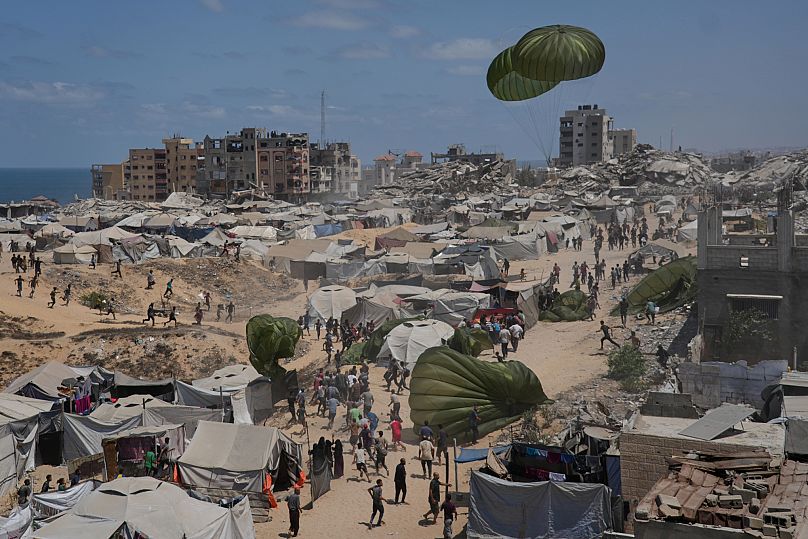 Palestinians rush to collect humanitarian aid airdropped by parachutes into Gaza City, 7 August, 2025