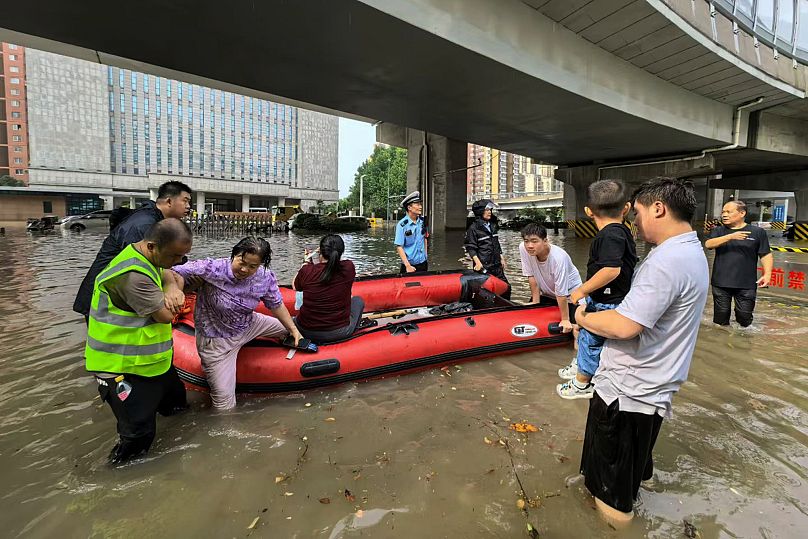 Rescuers use an inflatable boat to ferry people across a flooded road in Zhengzhou, 7 August, 2025