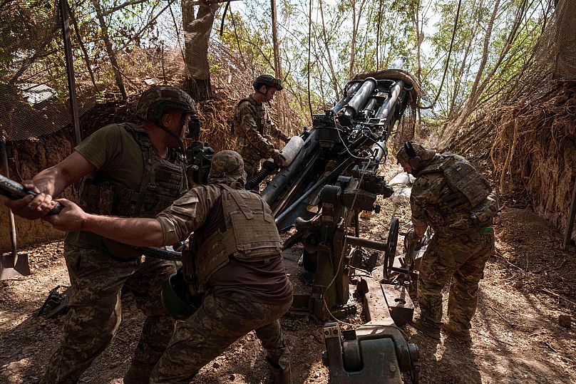 Ukrainian servicemen of the 148th artillery brigade load ammunition into a M777 howitzer before firing towards Russian positions in Zaporizhzhia, 7 August, 2025