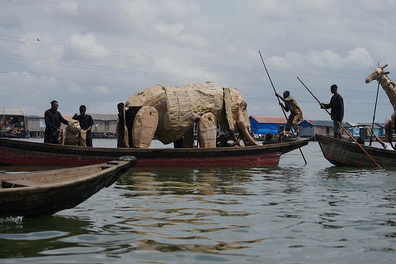 Puppeteers move cardboard animals in canoes at the Makoko Slum in Lagos Nigeria, 19 April 2025, as part of "The Herds,"