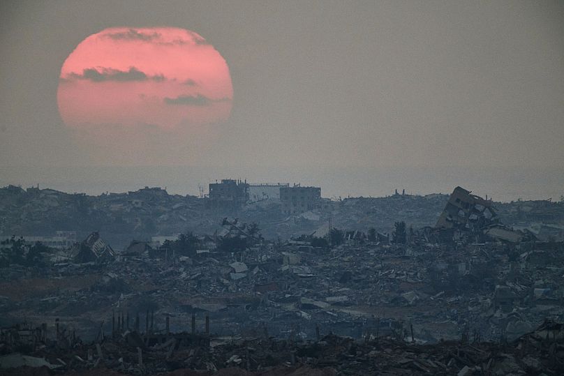 The sun sets behind buildings that were destroyed during the Israeli ground and air operations stand in the northern Gaza Strip, 8 August, 2025