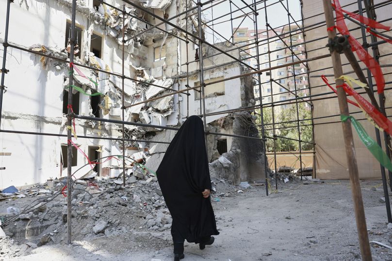 -امرأة تمشي أمام مبنى تضرر في غارة جوية إسرائيلية مميتة في 13 يونيو / حزيران على مجمع سكني في طهران ، إيران ، في 19 يوليو / تموز 2025.