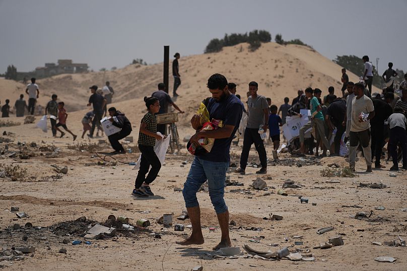 Palestinians collect humanitarian aid packages from the United Arab Emirates after they were airdropped into Deir al-Balah, in central Gaza Strip, Saturday, Aug. 9, 2025.