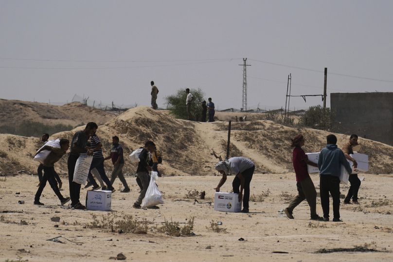 فلسطينيون يتلقون مساعدات غذائية أُسقطت جواً من الإمارات في دير البلح وسط غزة، 9 آب 2025.    