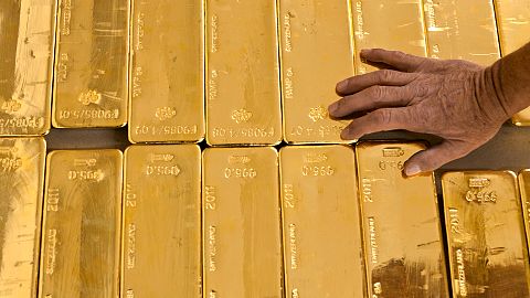 a person touches gold bars in the gold store of the Cantonal Bank of Zurich