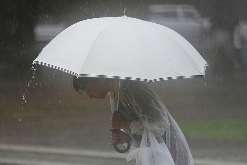 People bows to pray in the rain, at at the Atomic Bomb Hypocenter Park, ahead of a ceremony to commemorate the 80th anniversary of the Nagasaki atomic bomb, August 2025.
