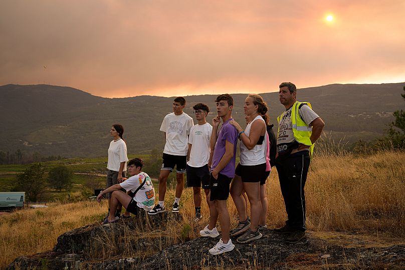 People watch the firefighting efforts as the fire progresses in A Cañiza, Pontevedra province, northwest Spain on Wednesday, July 30, 2025.