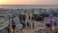 فلسطينيون نازحون يسيرون في مخيم عشوائي على شاطئ مدينة غزة، 10 أغسطس 2025.