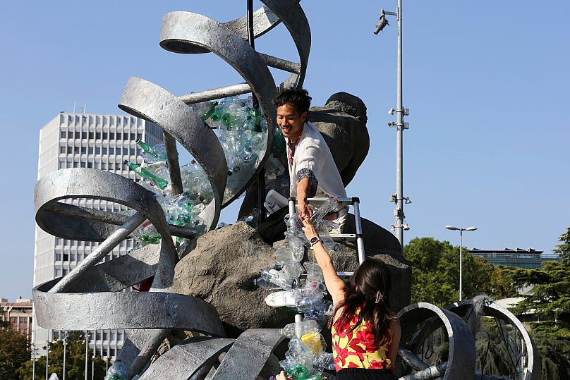 Benjamin Von Wong, top, a Canadian artist and activist, heaps piles of plastic waste onto a large sculpture that he designed in front of the United Nations office in Geneva.