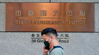 A man walks past the entrance of the headquarters of China Evergrande Group in Hong Kong Monday, Oct. 4, 2021.