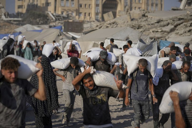 فلسطينيون يحملون أكياس طحين أُفرغت من قافلة مساعدات إنسانية، شمال القطاع، 31 يوليو 2025.    