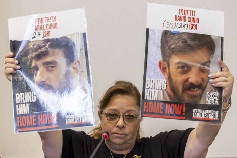 Silvia Cunio mother of the hostages Ariel Cunio, left, and David Cunio, right, holds pictures of her sons, during a press conference