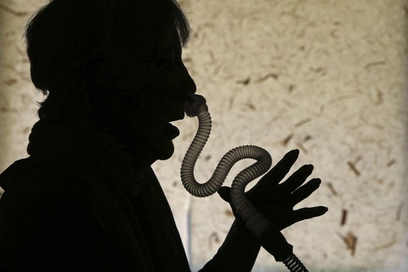 Uma mulher demonstra como coloca o seu aparelho respiratório para apneia do sono em sua casa, em Los Angeles, na quinta-feira, 12 de julho de 2018.