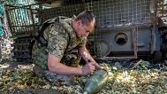 A soldier of Ukraine's 30th Mechanized Brigade writes a message on a howitzer shell to fire towards Russian positions on the front line near Kharkiv, Ukraine, Wednesday, Aug. 