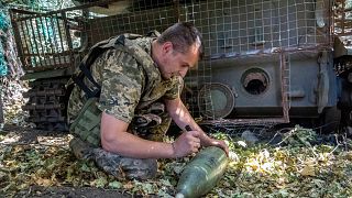 A soldier of Ukraine's 30th Mechanized Brigade writes a message on a howitzer shell to fire towards Russian positions on the front line near Kharkiv, Ukraine, Wednesday, Aug. 