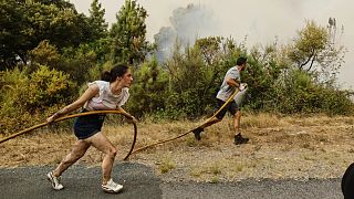 Residentes y voluntarios ayudan a sofocar las llamas en el incendio de Larouco el 13 de agosto de 2025.
