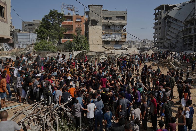 Palestinians struggle to collect humanitarian aid airdropped by parachutes into Gaza City, 14 August, 2025