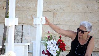 FILE: A woman touches the photo at the grave of her relative, killed in the 1974 Turkish invasion of Cyprus, in Nicosia, 20 July 2024