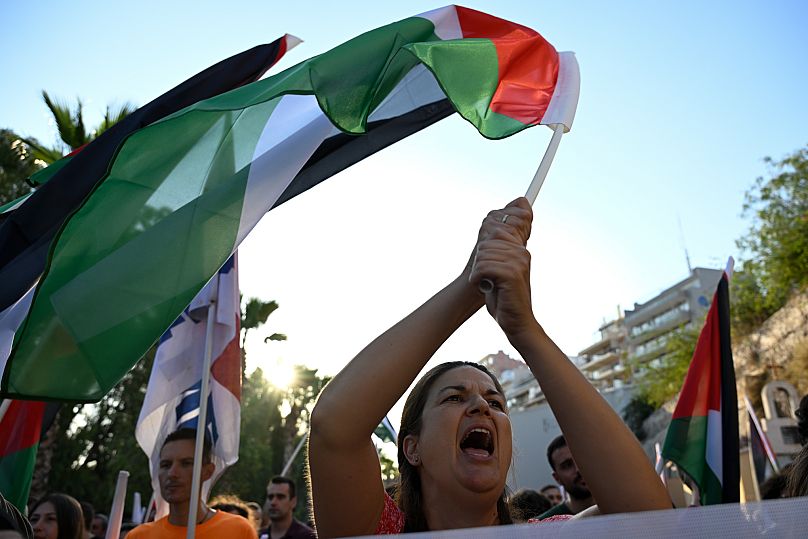A protester shouts slogans as she waves a Palestinian flag during a rally to protest the arrival of a cruise ship in Piraeus, 14 August, 2025