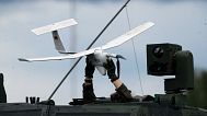 A soldier holds a drone atop of a NATO military vehicle rolling during a military exercising at the Training Range in Pabrade, some 60km north of the capital Vilnius