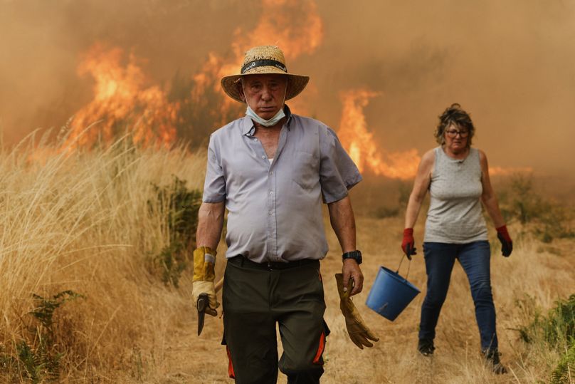 Des habitants réagissent devant le feu lors d'un incendie de forêt à Santa Baia De Montes, dans le nord-ouest de l'Espagne, le jeudi 14 août 2025. 