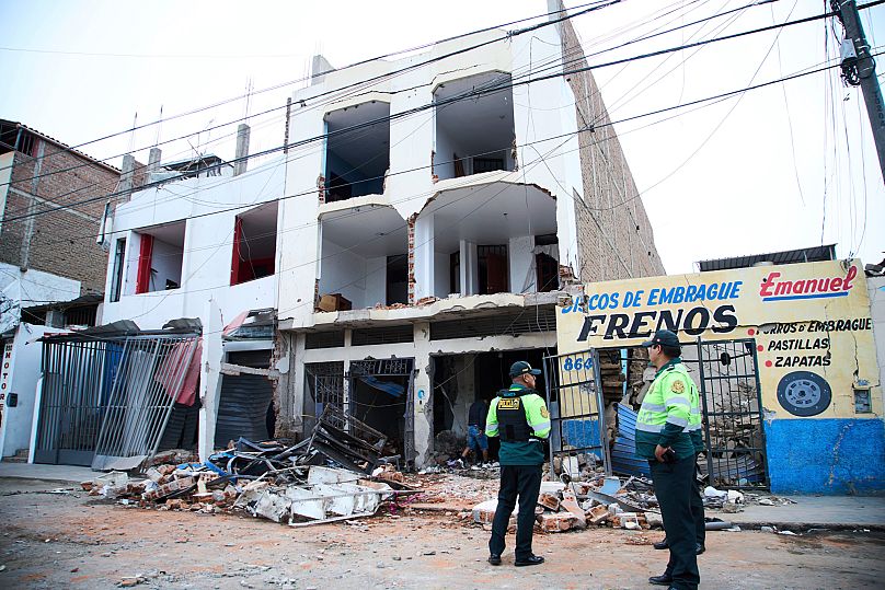 Police stand outside a building damaged by an explosion in Trujillo, 14 August, 2025