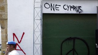 A U.N peacekeeper stands guards by a graffiti peace sign during a demonstration for the peace between Greek and Turkish Cypriots at the Ledras main crossing point.