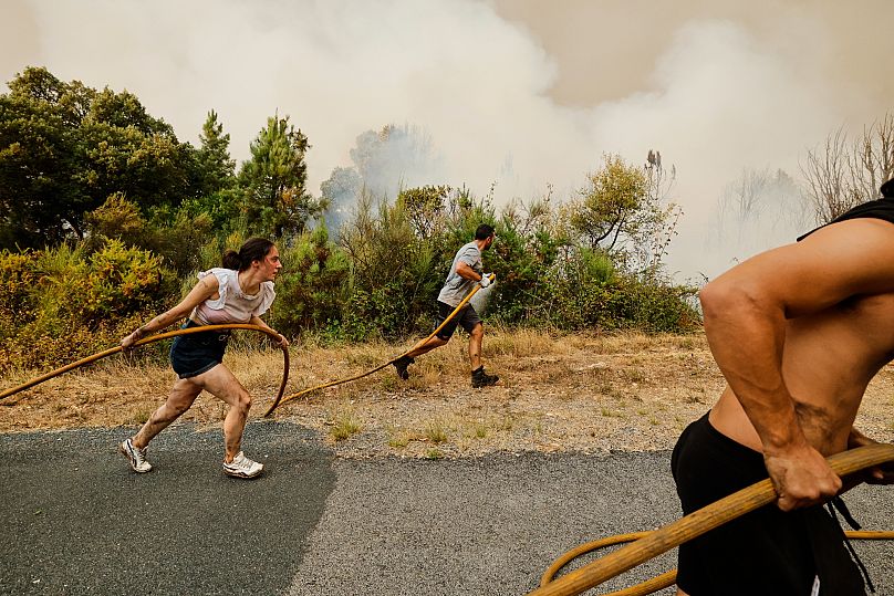 Des résidents et des volontaires combattent un incendie de forêt à Larouco, Espagne, le 13 août 2025.