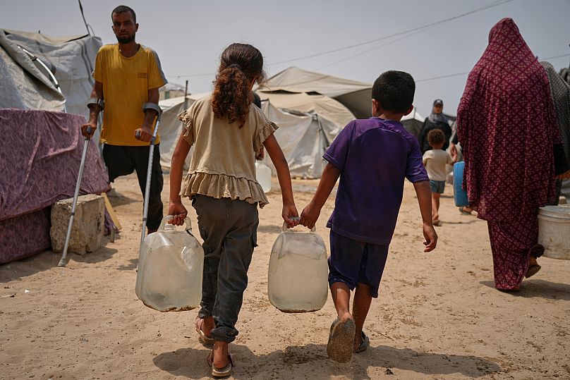 FILE: Palestinian children haul jerrycans of water collected from a distribution point in Gaza City, 12 August 2025