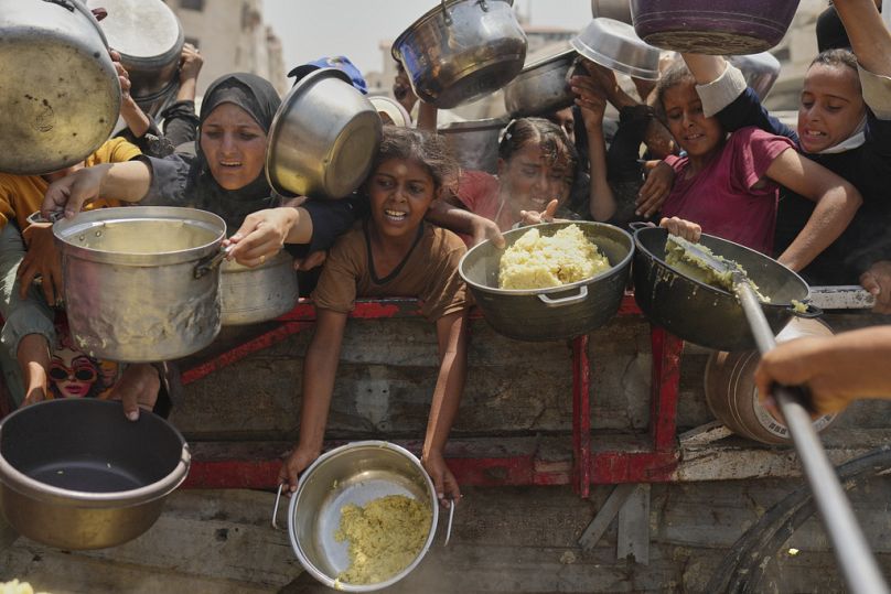 Palestinians struggle to get donated food at a community kitchen in Gaza City, northern Gaza Strip, Saturday, Aug. 16, 2025